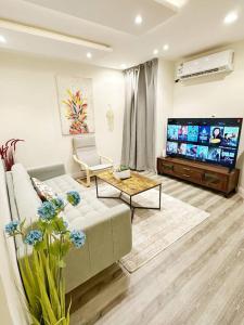 sala de estar con sofá y TV de pantalla plana en Luxury Apartment 201, en Riad