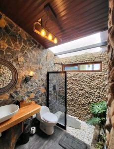 a bathroom with a toilet and a stone wall at PIKA CABINS 2 in San Carlos