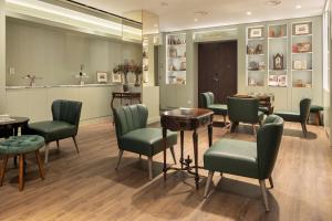 uma sala de espera com cadeiras e mesas verdes em The Emerald House Lisbon - Curio Collection By Hilton em Lisboa