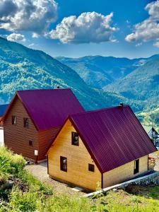 a barn with a purple roof with mountains in the background at Hotel Te Liqeni in Peje