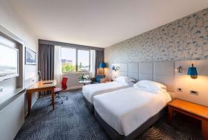 um quarto de hotel com duas camas e uma janela em Hilton Strasbourg em Estrasburgo
