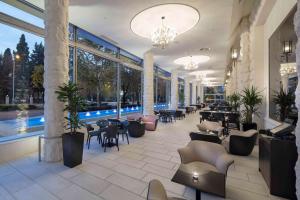 eine Lobby mit Tischen und Stühlen und einem Pool in der Unterkunft Hilton Podgorica Crna Gora in Podgorica