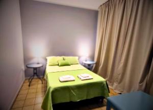 um quarto com uma cama verde com duas toalhas em Hotel Windsor Mendoza em Mendoza