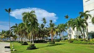 a park with palm trees in front of a building at Your Little Paradise - Juan Dolio in Juan Dolio