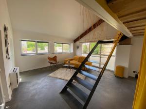 ein Wohnzimmer mit einer Treppe, die zu einem Loft führt in der Unterkunft Le Préau : charmante maison au bord de l’Isère in Bourg-de-Péage