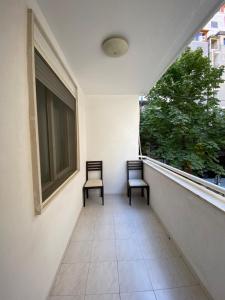 Duas cadeiras sentadas numa varanda com uma janela em Premier by Broci Apartments em Tirana