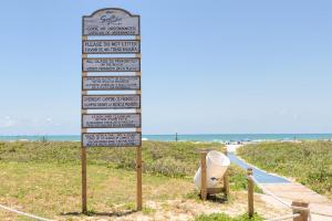 a sign in the grass next to a beach at 2-level condo next to beach w view of the Gulf! in South Padre Island
