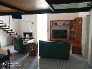 - un salon avec 2 chaises vertes et une télévision dans l'établissement Casa Fiore, à Monte di Procida