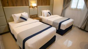 Habitación de hotel con 2 camas con sábanas blancas y azules en نسيم الشفا للشقق الفندقية en Taif