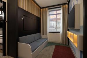 Zimmer mit Sofa, TV und Fenster in der Unterkunft Motto By Hilton Rotterdam Blaak in Rotterdam