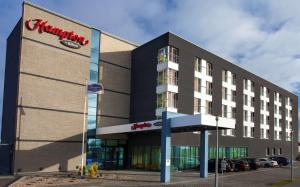 a hotel building with a sign on the front of it at Hampton by Hilton Gdansk Airport in Gdańsk-Rębiechowo