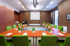een vergaderzaal met een lange tafel en groene stoelen bij Hampton by Hilton Gdansk Airport in Gdańsk-Rębiechowo