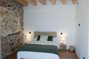 a bedroom with a white bed and a brick wall at El Esquileo in Buitrago del Lozoya
