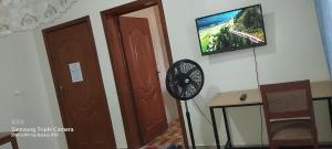 a room with a clock and a tv on the wall at HARRIET APARTHOTEL Kigali-NYARUTARAMA in Kigali