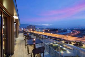 balcone con tavoli, sedie e vista sulla città di DoubleTree By Hilton Skopje a Skopje