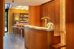 - un bar dans un restaurant avec des murs orange et des tabourets dans l'établissement Le Belgrand Hotel Paris Champs Elysees, Tapestry By Hilton, à Paris