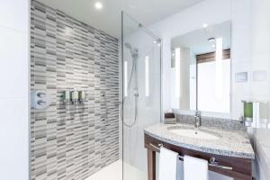 a white bathroom with a shower and a sink at Hampton by Hilton Oswiecim in Oświęcim