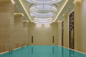 een zwembad in een kamer met een kroonluchter bij Hilton Dushanbe in Doesjanbe