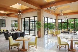 ein Restaurant mit Tischen, Stühlen und Fenstern in der Unterkunft Hilton Dushanbe in Duschanbe