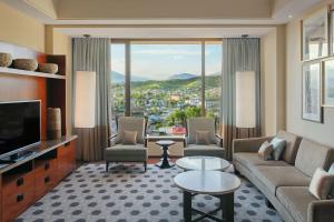 Hilton Dushanbe في دوسهانبي: غرفة معيشة بها أريكة وكراسي وتلفزيون