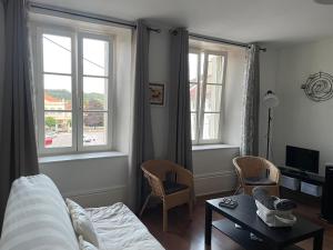 a living room with a bed and two windows at Grand appartement centre ville quartier calme in Neufchâteau