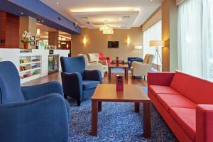 a waiting room with couches and chairs and a table at Hampton by Hilton Warsaw Airport in Warsaw