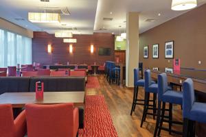 una sala de espera con mesas, sillas y TV en Hampton by Hilton Warsaw Airport en Varsovia