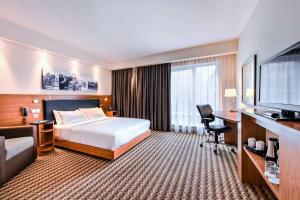 a hotel room with a bed and a desk and a television at Hampton by Hilton Warsaw Airport in Warsaw
