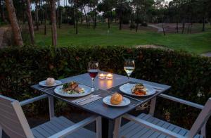 einen Tisch mit Teller mit Speisen und zwei Gläsern Wein in der Unterkunft DoubleTree by Hilton Islantilla Beach Golf Resort in Islantilla