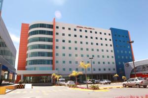 a large building with cars parked in a parking lot at Hampton Inn & Suites by Hilton Aguascalientes Aeropuerto in Aguascalientes