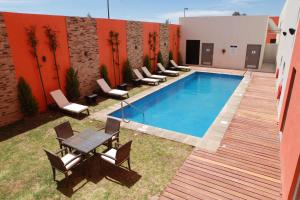 a swimming pool with chairs and a table next to a building at Hampton Inn & Suites by Hilton Aguascalientes Aeropuerto in Aguascalientes