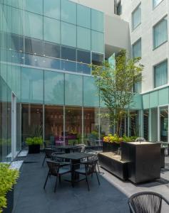 une cour avec des tables et des chaises devant un bâtiment dans l'établissement Hampton by Hilton Aguascalientes Downtown, à Aguascalientes