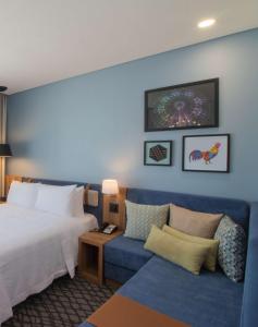 a hotel room with a bed and a blue couch at Hampton by Hilton Aguascalientes Downtown in Aguascalientes