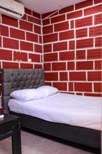 a red brick wall with a bed in a room at Hostal La Guaca in Cartagena de Indias