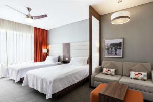 a hotel room with two beds and a couch at Homewood Suites By Hilton Silao Airport in Silao