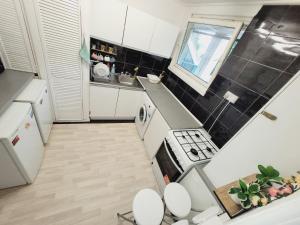 uma pequena cozinha com electrodomésticos brancos e azulejos pretos em EXCELLENT DOUBLE ROOMS IN CHEAP RATE AROUND CENTRAL LONDON em Londres