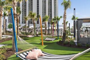 a hammock in a park with palm trees and a building at Embassy Suites by Hilton Myrtle Beach Oceanfront Resort in Myrtle Beach