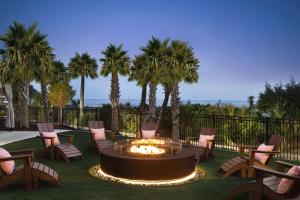 eine Terrasse mit Stühlen und eine Feuerstelle mit Palmen in der Unterkunft Embassy Suites by Hilton Myrtle Beach Oceanfront Resort in Myrtle Beach