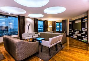 a living room with couches and chairs and windows at Hilton Bogotá in Bogotá