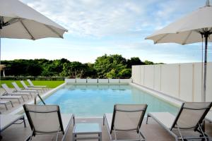 a swimming pool with chairs and umbrellas at Hampton Inn by Hilton Ciudad del Carmen in Ciudad del Carmen