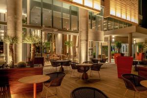 Hilton Garden Inn Chihuahua في تشيواوا: لوبي فيه طاولات وكراسي في مبنى