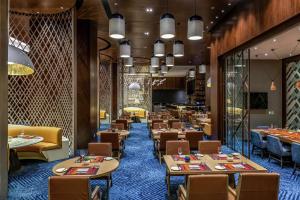 a dining room with tables and chairs and a restaurant at Hilton Guadalajara Midtown in Guadalajara