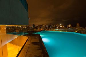 a swimming pool with a view of the city at night at Hilton Lima Miraflores in Lima