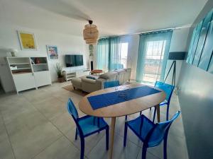 ein Wohnzimmer mit einem Tisch und blauen Stühlen in der Unterkunft T3 BLUE PORT - 4 étoiles + 2 Loggias + 2 Parkings in Marseillan