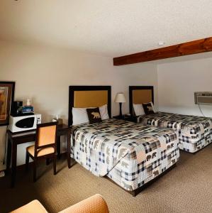 a hotel room with two beds and a desk at Holiday Lodge in Cody