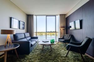 Hampton By Hilton Montevideo Carrasco في مونتيفيديو: غرفة معيشة مع أريكة زرقاء وكرسيين