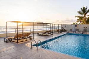 una piscina con sillas y el océano en el fondo en DoubleTree by Hilton Mazatlan, SIN, en Mazatlán