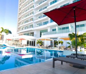 uma piscina com um guarda-sol vermelho e um edifício em DoubleTree by Hilton Mazatlan, SIN em Mazatlán
