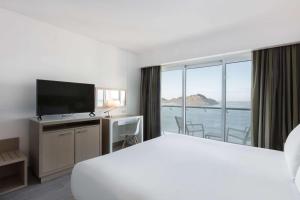 una camera d'albergo con un grande letto e una grande finestra di DoubleTree by Hilton Mazatlan, SIN a Mazatlán