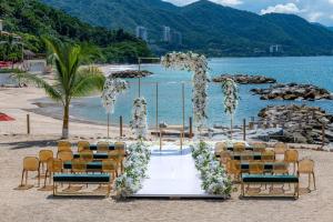 a wedding ceremony setup on a beach with chairs at Hilton Vallarta Riviera All-Inclusive Resort,Puerto Vallarta in Puerto Vallarta
